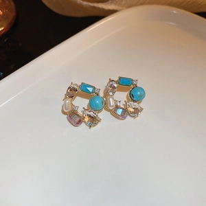 Détail des boucles d'oreilles fleurs en cristal coloré avec turquoise et perles sur porcelaine