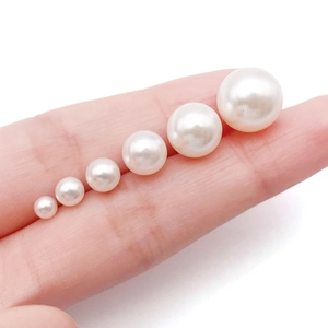Detail view of five gradient sizes of white pearls on finger for size comparison
