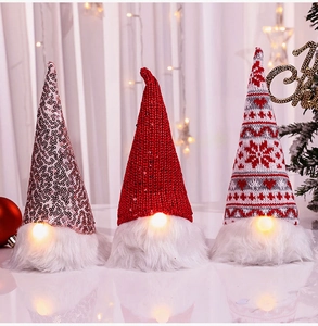 Three Christmas gnomes with LED lights, sequins, and knit hats on warm festive background
