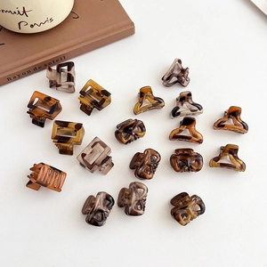 Mini leopard print hair claws in tortoiseshell colors scattered on a white surface