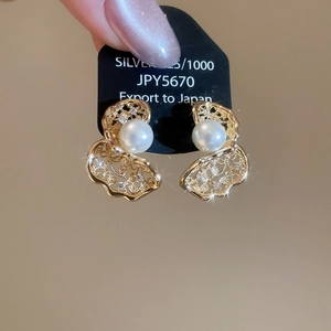 Macro view of gold lace-edged pearl earrings with zircon inlay on a 925 silver base