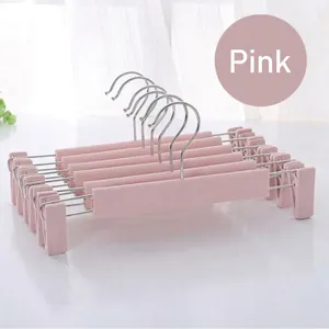 Detail of adjustable clips on dusty pink non-slip pants hangers for home organization