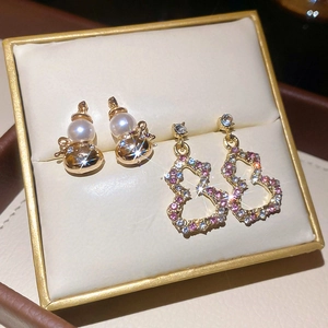 Detailed close-up of golden gourd pearl earrings with colorful pavé rhinestones