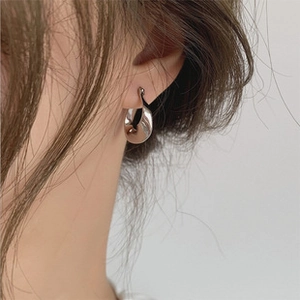 Polished silver-tone twisted C-shape earrings shown on a model for a modern minimalist look