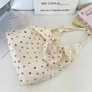 Gros plan détaillé d'un sac cabas en toile crème à pois colorés avec une bandoulière large