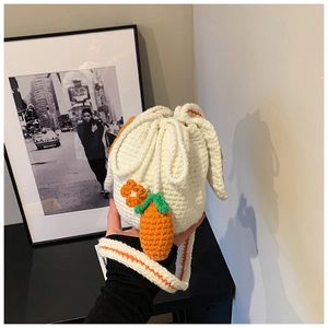 Detail of handmade crochet bunny bucket bag with carrot and orange flower charms