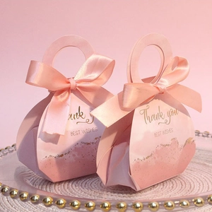 Detail of two pink wedding candy boxes with satin ribbons and golden thank you text