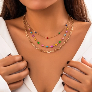 Close-up of layered gold chains with colorful enamel beads on a female model