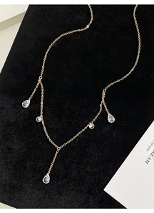 Detailed close-up of golden tassel necklace with zircon water drop pendants on black velvet