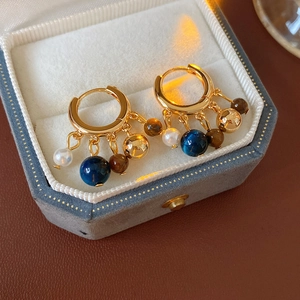 Detail of vintage beaded tassel earrings with pearls and tiger eye stones in a velvet box