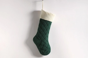 Detail of dark green knit Christmas stocking with ivory cuff and cable stitch texture