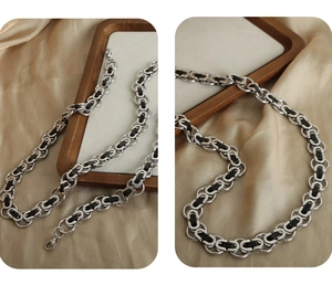 Detailed view of punk geometric silver chain necklace on a tray with silk background