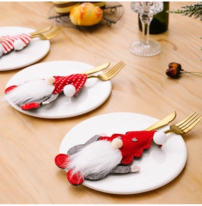 Close-up of festive Christmas gnome cutlery holders with golden forks on a white plate
