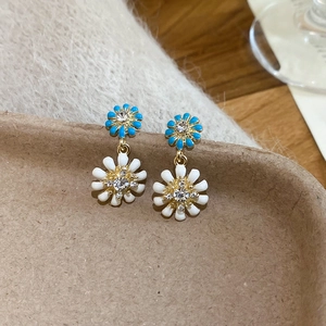 Macro detail of layered daisy drop earrings with blue and white petals and crystal center