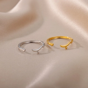 Close-up of gold and silver heart-shaped open rings on elegant beige silk fabric