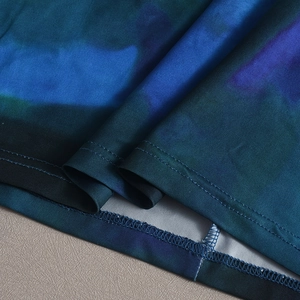 Détail du tissu à imprimé floral abstrait bleu et violet avec surpiqûres à double aiguille