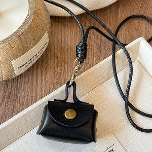Close-up of mini black leather earphone case with gold clasp on wooden table decoration