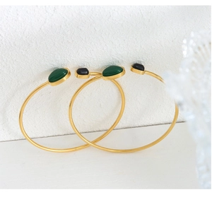 Close-up of gold titanium steel bracelets with oval green and black agate stones