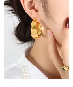 Close-up of 18K gold plated U-shaped thick hoop earrings worn by a model for a chic look