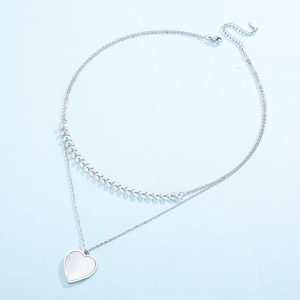Silver double-layered chain necklace featuring a polished heart pendant on a blue background