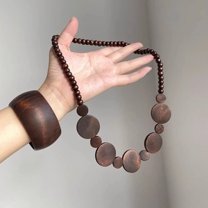 Detailed texture of bohemian dark walnut wood bead necklace and matching wide wooden bangle