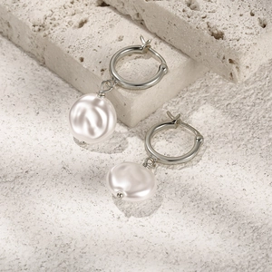 Close-up of elegant baroque pearl earrings on a textured stone surface with fine detail