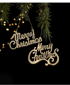 Close-up of golden Merry Christmas iron ornament hanging on a festive tree branch