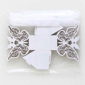 Flat lay of white laser-cut butterfly favor box with ribbon in clear packaging