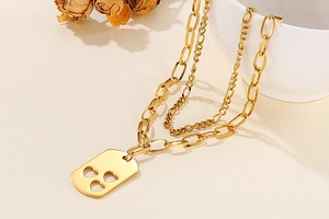 Detail of gold double-layered necklace featuring paperclip chain and hollow heart pendant