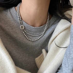 Detail of double-layer silver beaded necklace with a vintage square green gemstone pendant