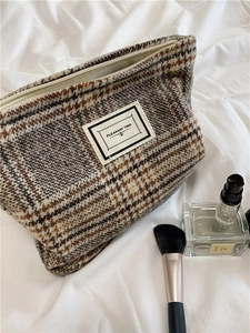 Close-up of a plaid wool makeup bag with a PLEASANT TIME label and zipper detail