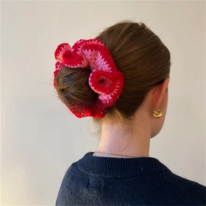 Close-up of handmade crochet flower scrunchie in red and pink colors on bun