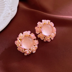 Detail of pink floral earrings with central bead on silk background for a classic vintage look
