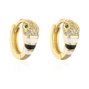 Macro detail of gold-plated snake hoop earrings with enamel stripes and green gem eyes
