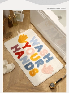 Thick plush bathroom mat with Wash Your Hands text placed by a modern bathtub