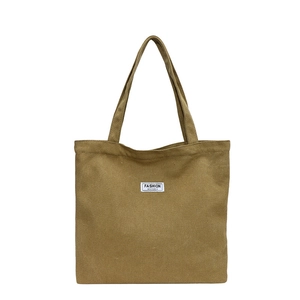 Olive green canvas tote bag with black lettered fashion label on a white background