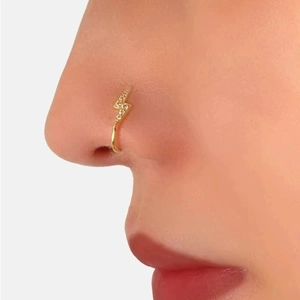 Close-up of golden lightning bolt nose ring with small sparkling crystals on model