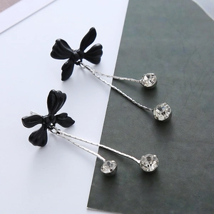 Détail de boucles d'oreilles longues avec nœuds papillon noirs et pendentifs zircon