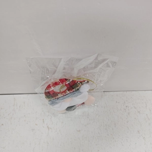 Detail eines Weihnachtsgnom-Plüschtiers in Verpackung mit rot-kariertem Hut und Goldkordel