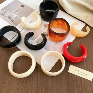 Retro geometric acrylic resin open bangles and closed rings in multiple colors on wood