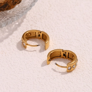 Macro detail of gold plated twisted hoop earrings with sparkling inlaid rhinestones