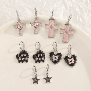 Flat lay of diverse silver earrings featuring pink hearts, black cats, and star designs