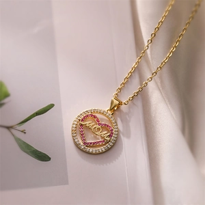 Detail of gold-plated MOM heart pendant with pink zircon on soft white silk backdrop