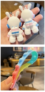 Close-up of cute 3D silicone space bunny astronaut keychains and colorful pop-it wristband