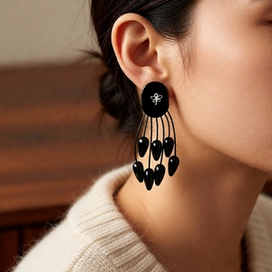 Gros plan de boucles d'oreilles à pompons noirs avec clous ovales et détails argent
