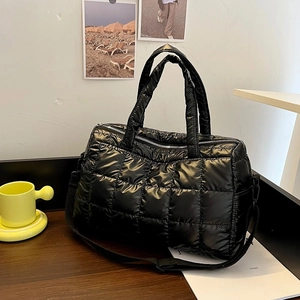 Chic black quilted puffer handbag with adjustable crossbody strap on a rustic table