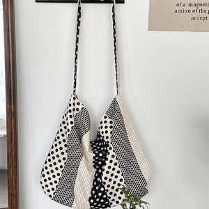 Detail of large black and white polka dot canvas tote bag hanging in a minimalist room