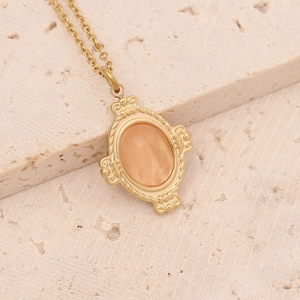 Close-up of golden necklace with an oval orange natural stone in an ornate frame