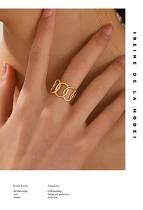 Close-up of a gold geometric interlocking link ring on a finger with a minimalist design