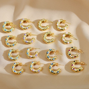 Gold C-shaped earrings featuring colorful evil eye enamel patterns and sparkling crystals